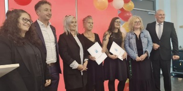 Ein Gruppenfoto bestehend aus zwei Männern und fünf Frauen. Zwei Frauen halten ein Zeugnis in der Hand.